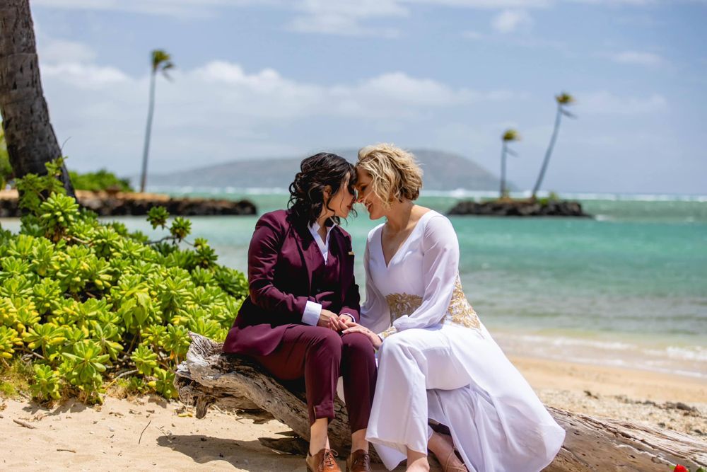 Annie and Sam sitting forehead to forehead on a beach