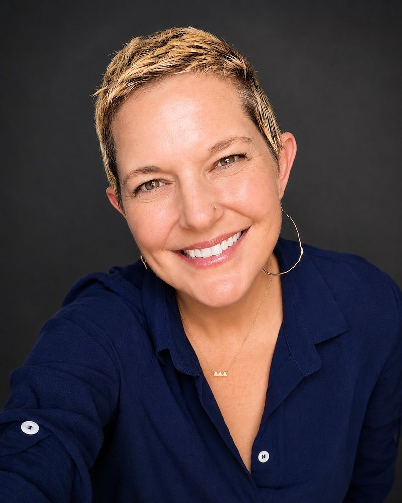 Headshot of Annie M. Henderson, Navy Top, Dark Background