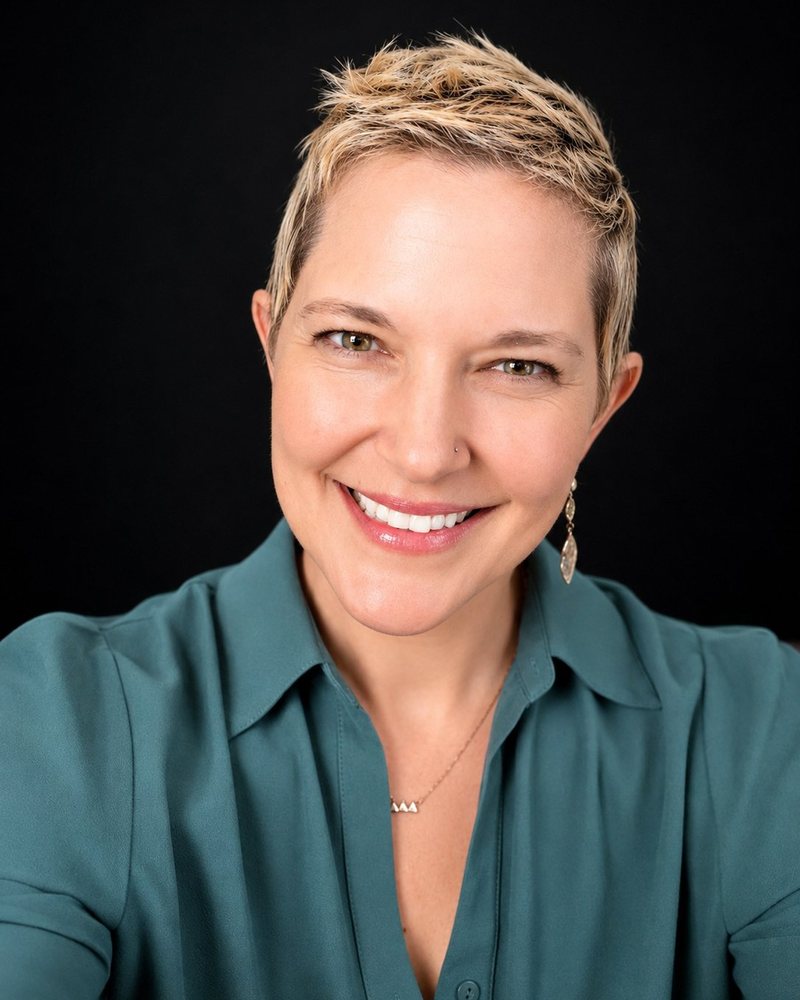 Headshot of Annie M. Henderson, Teal Top, Black Background